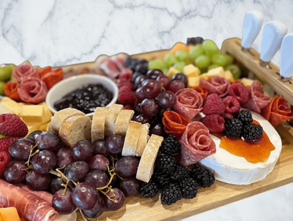 A vibrant charcuterie board with grapes, berries, cured meats, and cheeses.