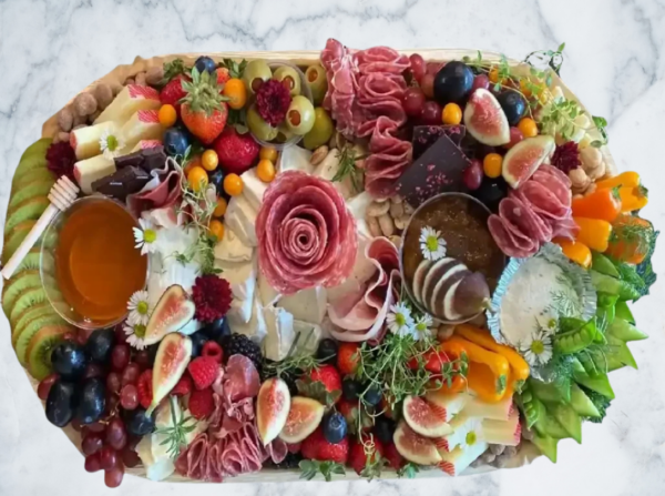A colorful charcuterie board with meats, cheeses, fruits, and nuts.