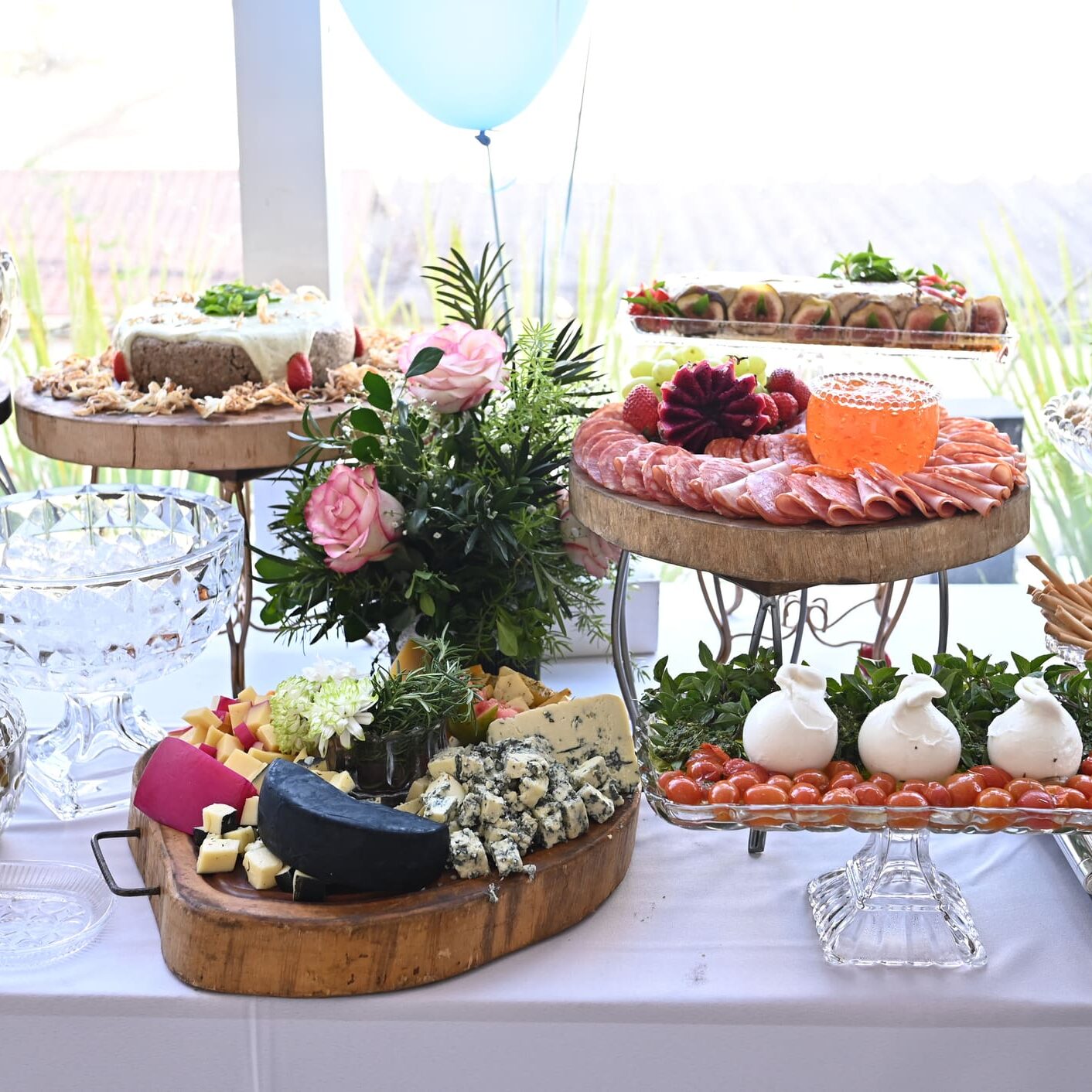 A beautifully arranged dessert table with cakes, flowers, and balloons.